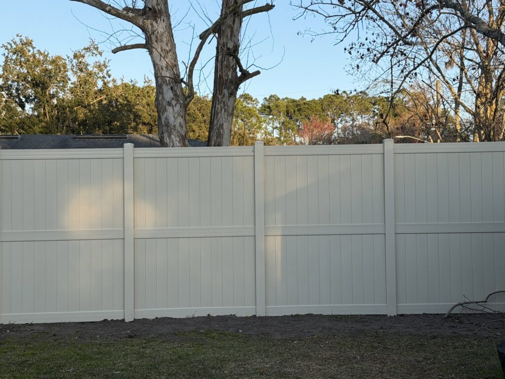 A tan vinyl privacy fence installed in a residential area by Masters Fence Contracting in Jacksonville, FL.