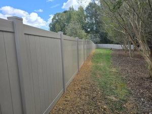 A long tan vinyl privacy fence installed along a property line by Outsiders Fencing in Greensboro, NC.
