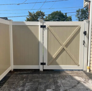 A newly installed tan and white vinyl fence gate with black hardware, completed by Discount Fence Supply in Great Falls, SC.