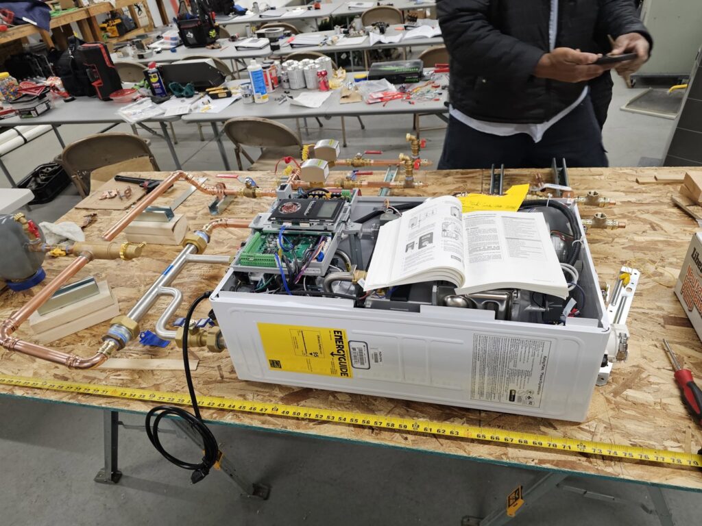 A tankless water heater unit being assembled or serviced on a workbench by Perfect Temp LLC in Bozeman, MT.
