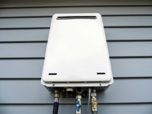 A white tankless water heater professionally installed on an exterior wall by Evergreen HVAC Comfort Solutions in Milwaukee, WI.