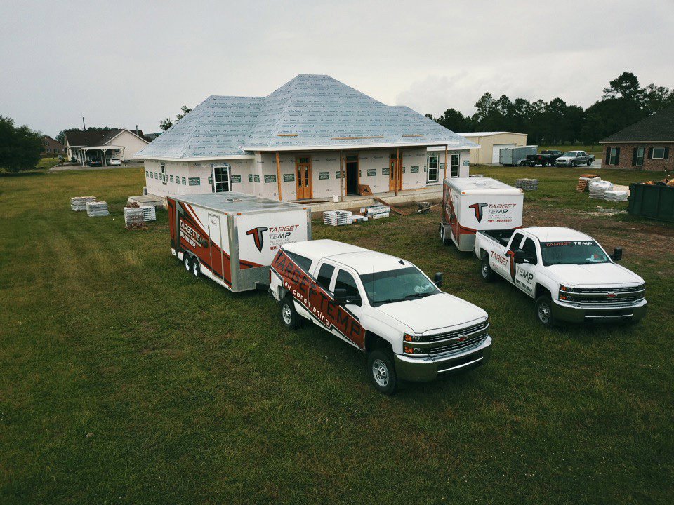 Target Temp, LLC trucks and trailers at a new home construction site in Houma, LA, ready for HVAC installation.