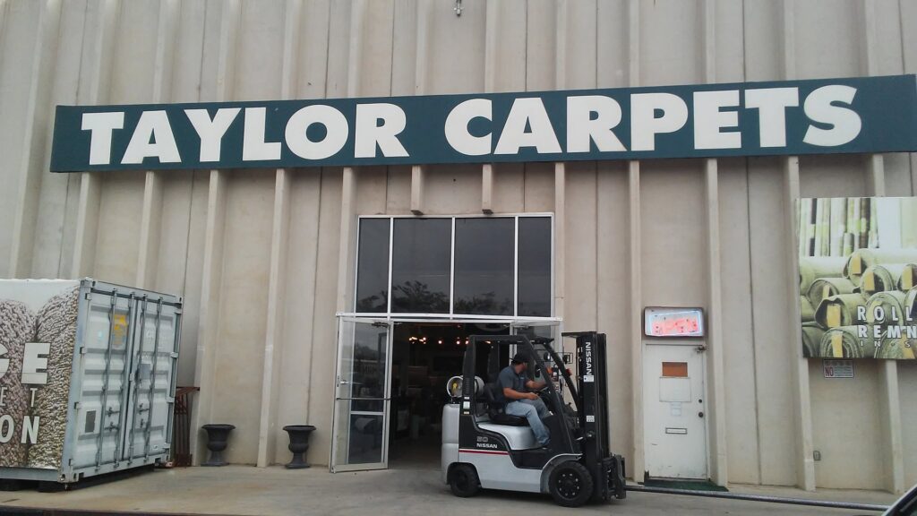 The exterior storefront of Taylor Carpets & Flooring with a forklift outside in Provo, UT