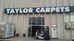 The exterior storefront of Taylor Carpets & Flooring with a forklift outside in Provo, UT