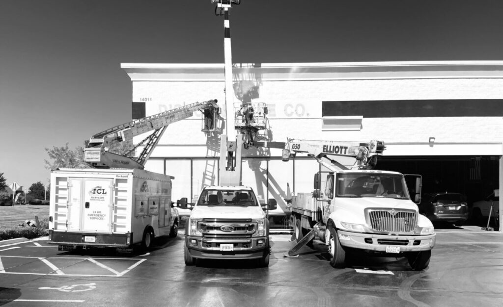 Fleet of TCL Electrical and Lighting service trucks with boom lifts parked in North Aurora, IL