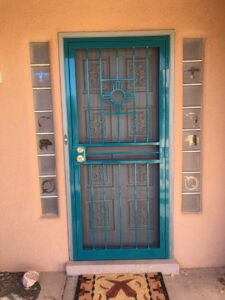 A teal security screen door featuring a New Mexico Zia symbol, installed by City Iron LLC in Albuquerque, NM.
