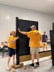 A team of workers assembling a solar fence panel indoors, showcasing the product of Sol Fence LLC in Evansville, IN.