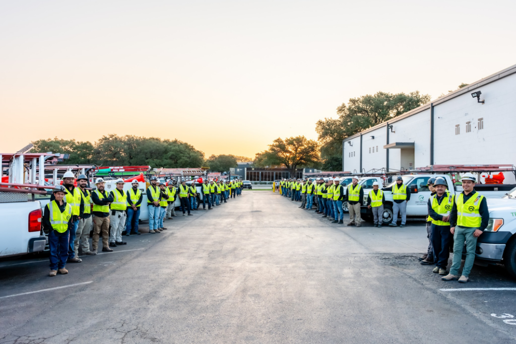 A large team of electricians with service trucks lined up at Crest Electrical Solutions in Arlington, TX.