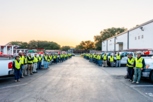 A large team of electricians with service trucks lined up at Crest Electrical Solutions in Arlington, TX.