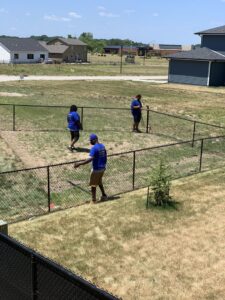 A team from Stallworth Home Improvement installing a black chain-link fence in a residential backyard in Des Moines, IA.