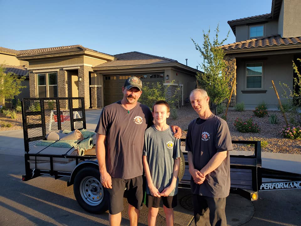 Team members with rolled carpets on a trailer, ready for transport by Aaron's Carpet Care LLC in Peoria, AZ.