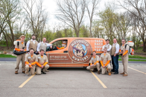 A team of Mosquito Hunters technicians with backpack sprayers and a branded van in Cedar Rapids, IA.
