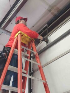 A technician adjusting garage door springs and tracks for Garage Door Specialists Of Oklahoma Inc. in Oklahoma City, OK