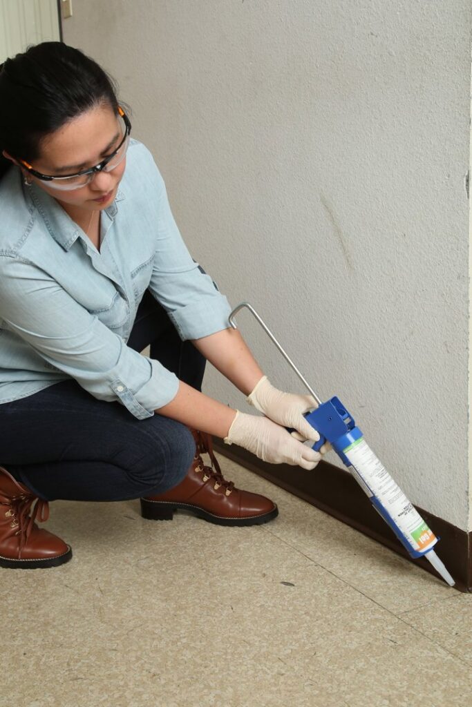 A Detourgel technician applying pest control gel with a caulk gun along a wall in Whittier, CA.