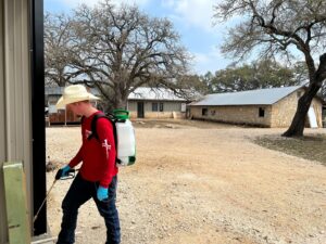 A Blessed Pest Control technician applying an exterior pest treatment to a building in San Antonio, TX