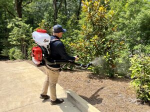 A technician from Birmingham Pest & Mosquito Control applying mosquito treatment to a residential yard's foliage in Birmingham, AL.