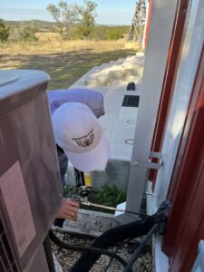 A Blessed Pest Control technician applying foam sealant for pest exclusion around an exterior pipe in San Antonio, TX