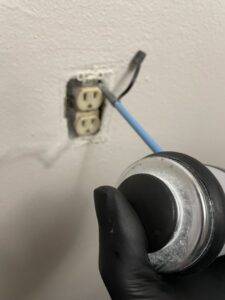 A technician applying pest treatment into an electrical outlet, a common method used by Pike Creek Exterminating in Kenosha, WI.