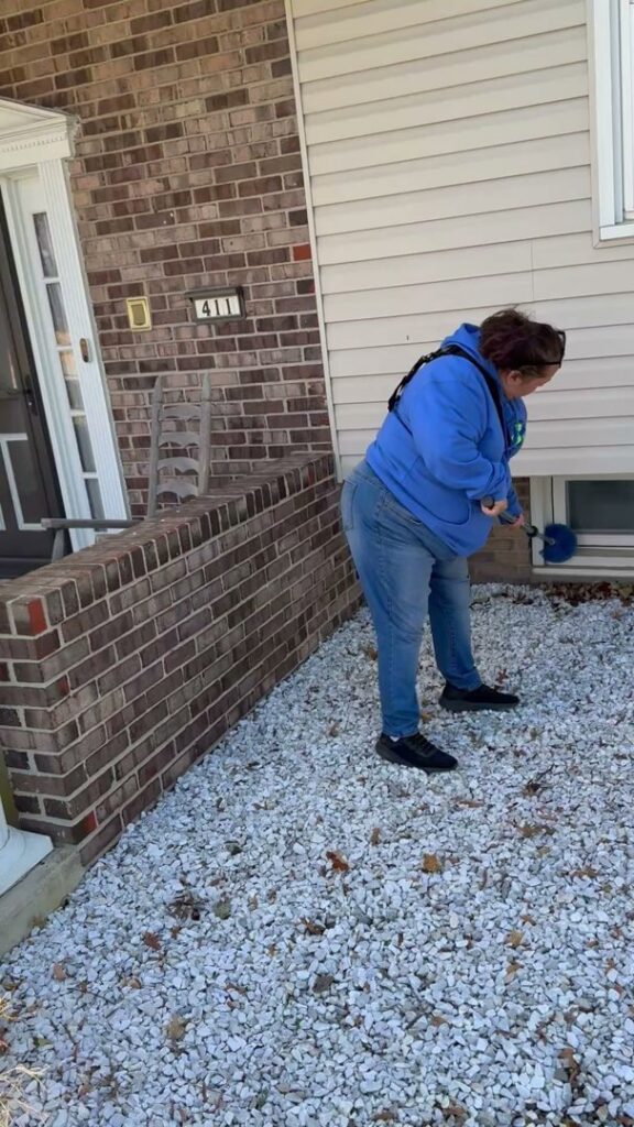 A pest control technician applying treatment around a home's exterior, provided by Genesis Termite and Pest Control in New Holland, PA.