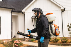 A pest control technician applying treatment to the exterior of a home for The Pest Detective in Cleveland, OH.