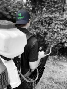 A Sustainable Pest Systems technician applying pest treatment with a backpack sprayer in Raleigh, NC.