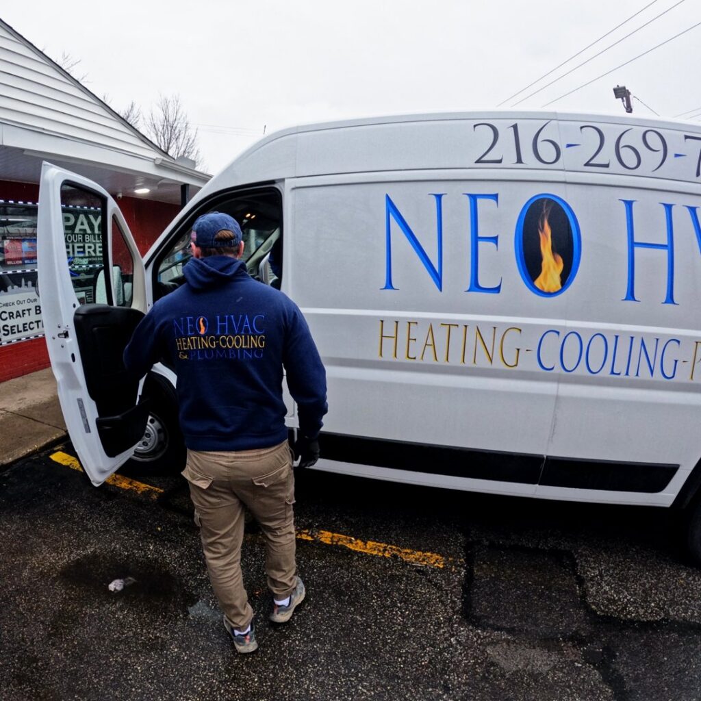 A technician from North East Ohio Master Plumbing, Heating, and Cooling Contractors arriving in a service van in Cleveland, OH.