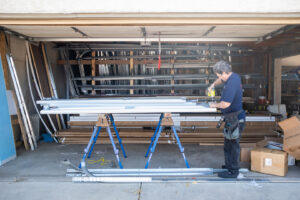 A garage door technician assembling new garage door panels on sawhorses inside a garage for Above The Rest Garage Door in Colorado Springs, CO.