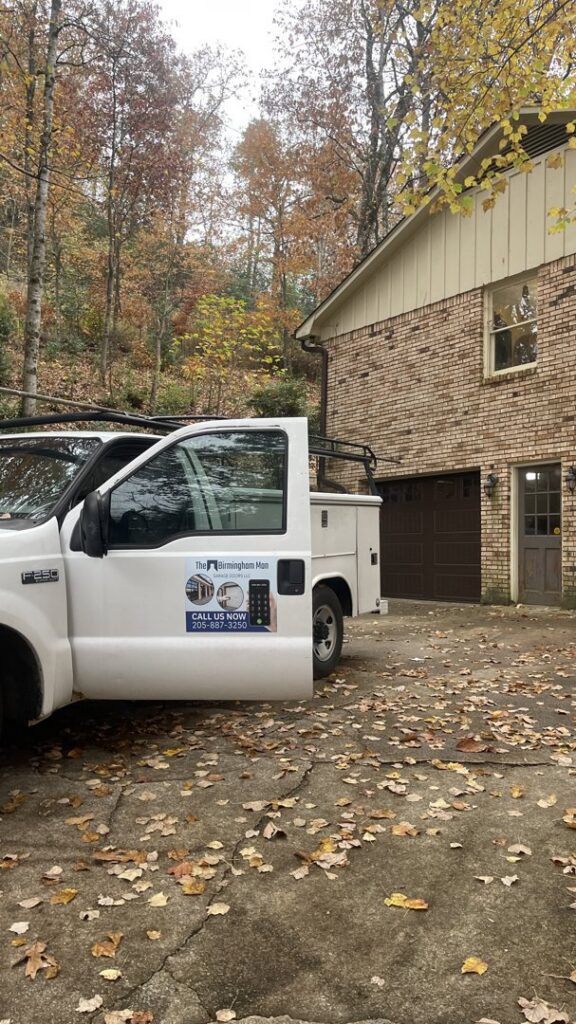 A technician's truck from The Birmingham Man Garage Doors at a job site with a brown garage door in Birmingham, AL.