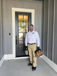 A Hemi Pest Control technician standing at a front door with a sprayer and tool bag, ready for service in Meridian, ID.