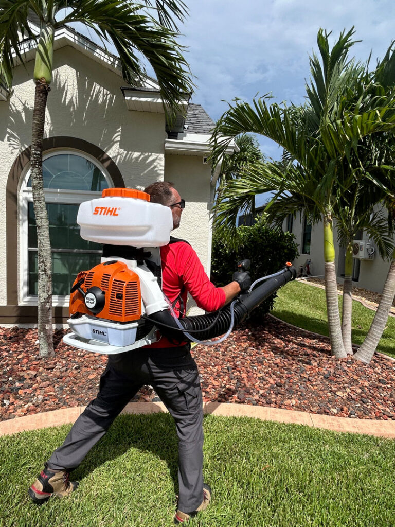 A Paske Pest Control & Wildlife Solutions technician using a backpack sprayer for outdoor pest control in Cape Coral, FL.