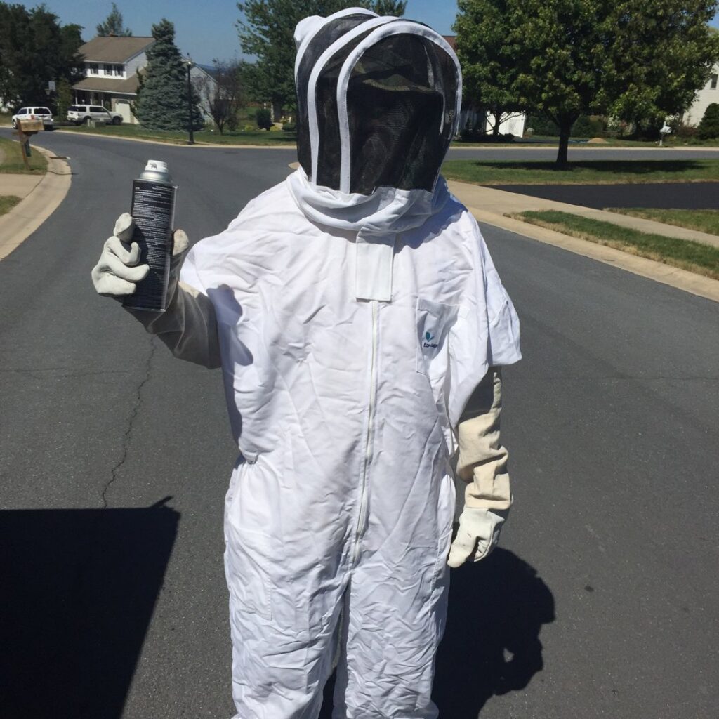 A pest control technician in a full bee suit holding a spray can, ready for a job with Genesis Termite and Pest Control in New Holland, PA.
