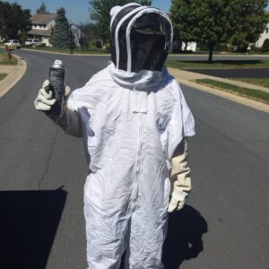 A pest control technician in a full bee suit holding a spray can, ready for a job with Genesis Termite and Pest Control in New Holland, PA.