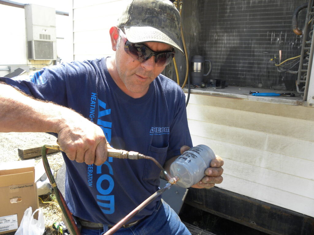 An AireCom HVAC technician brazing copper lines during a service job in Columbus, OH.