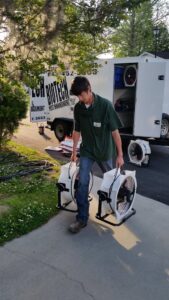 A Biotech Pest Management technician carrying fans for thermal remediation pest control in Summerville, SC.