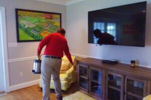 A technician carrying a pest control device in a living room at Rice's, Inc. Termite & Pest Control in Salisbury, MD