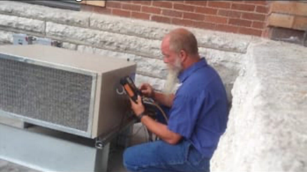 A Wes-Tech Services technician performing maintenance on an outdoor commercial HVAC unit in Bloomington, IN.
