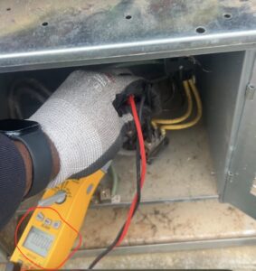A technician using a multimeter to check the electrical panel of an HVAC unit for A/C Company Since 1988 in Murfreesboro, TN.