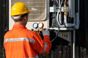 A technician checking an outdoor HVAC unit with gauges for Chrismon Heating & Cooling in Greensboro, NC.