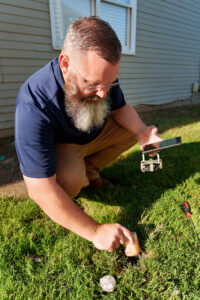 A Pest Magic Pest Control technician checking a pest bait station in a residential lawn in Forsyth, GA.