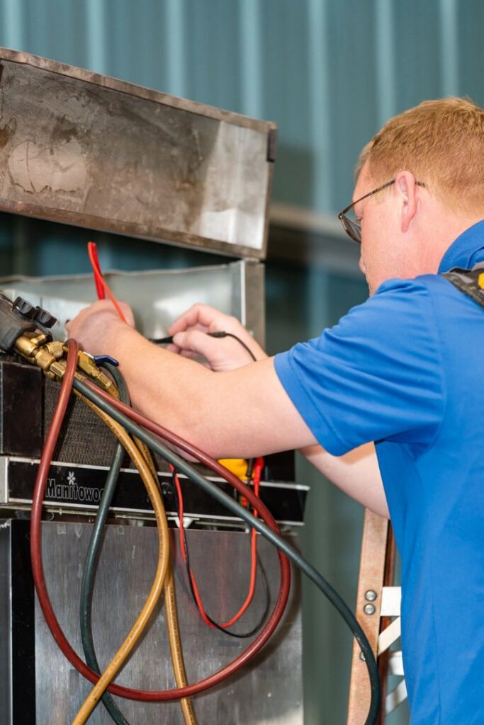 A Beman's Sales & Service technician checking refrigerant levels with a digital manifold gauge in Hastings, NE.