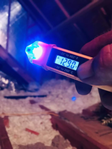 A technician checking the temperature in an attic with a digital thermometer for Brady Air & Home Repair LLC in Asheboro, NC.