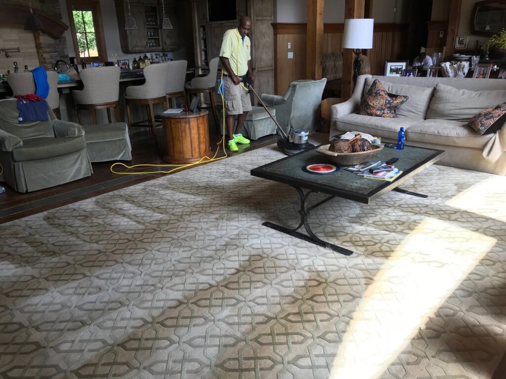 A technician from Johns Creek Carpet Cleaner cleaning a large area rug in a living room in Johns Creek, GA.
