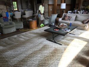 A technician from Johns Creek Carpet Cleaner cleaning a large area rug in a living room in Johns Creek, GA.