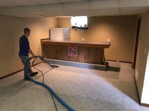 A technician from Mark's Carpet Cleaning cleaning a basement carpet with professional equipment in Omaha, NE
