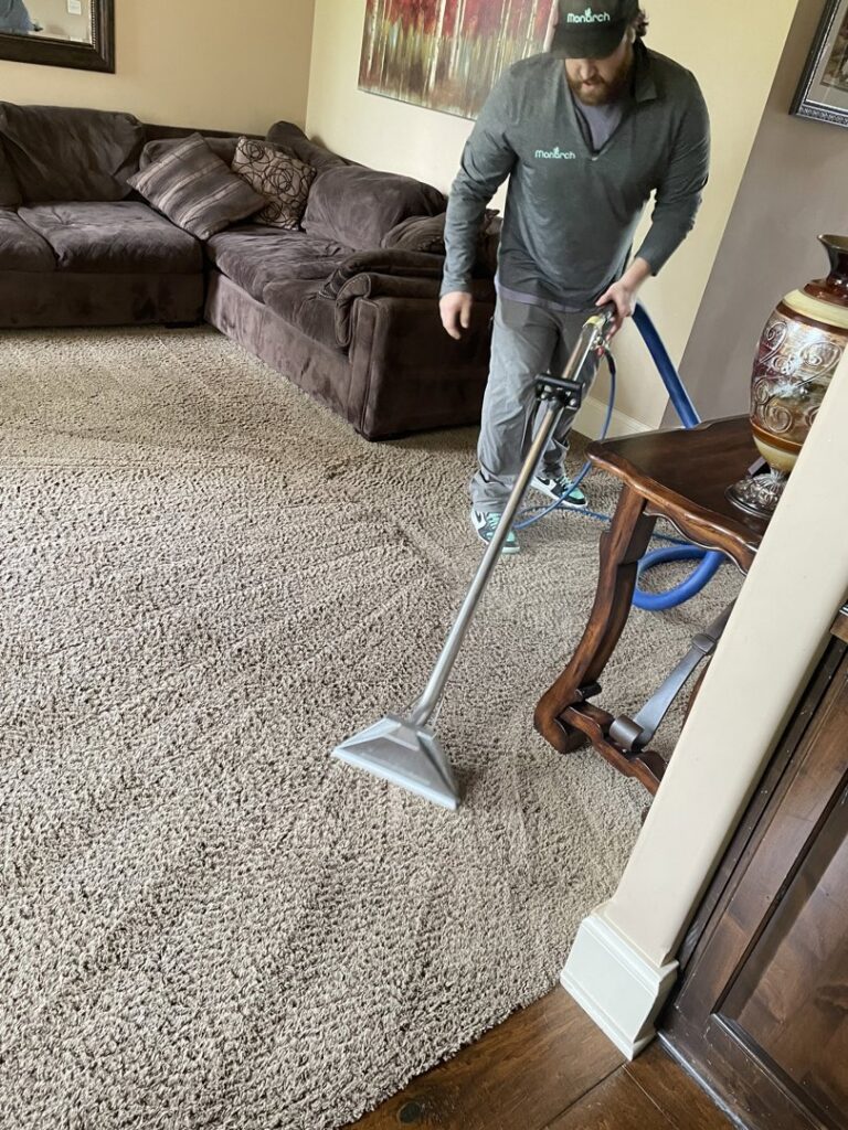 A technician from Monarch Cleaning Solutions cleaning a brown carpet in a living room in Parkville, MO