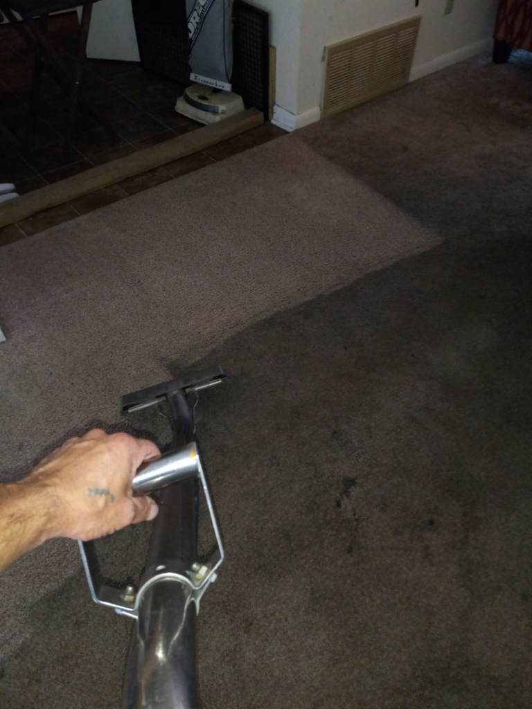 A technician's hand guiding a carpet cleaning wand, showing a clean path by C&S Carpet Cleaning in Cyril, OK.
