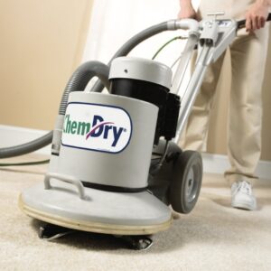 A K&T Chem-Dry technician professionally cleaning a light-colored carpet with a Chem-Dry machine in New Lenox, IL.