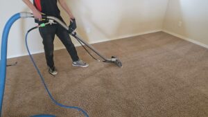 A technician cleaning carpet with a professional wand at a client's home by KD Carpet Cleaning in Cape Coral, FL