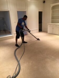 A technician from TLC Carpet Cleaning, Inc. cleaning a light-colored carpet in a large room in Lewisville, TX.