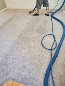 A technician operating a carpet cleaning wand on a light-colored carpet for Super Clean Carpet Cleaning in Idaho Falls, ID.